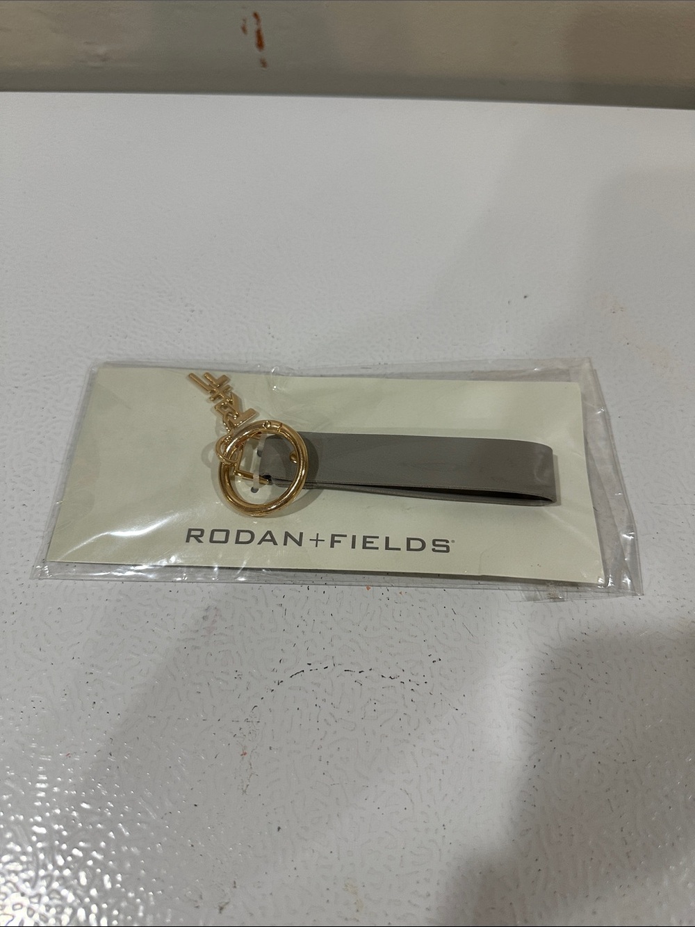 Rodan + Fields Gray Leather Strap Keychain with Gold Hardware